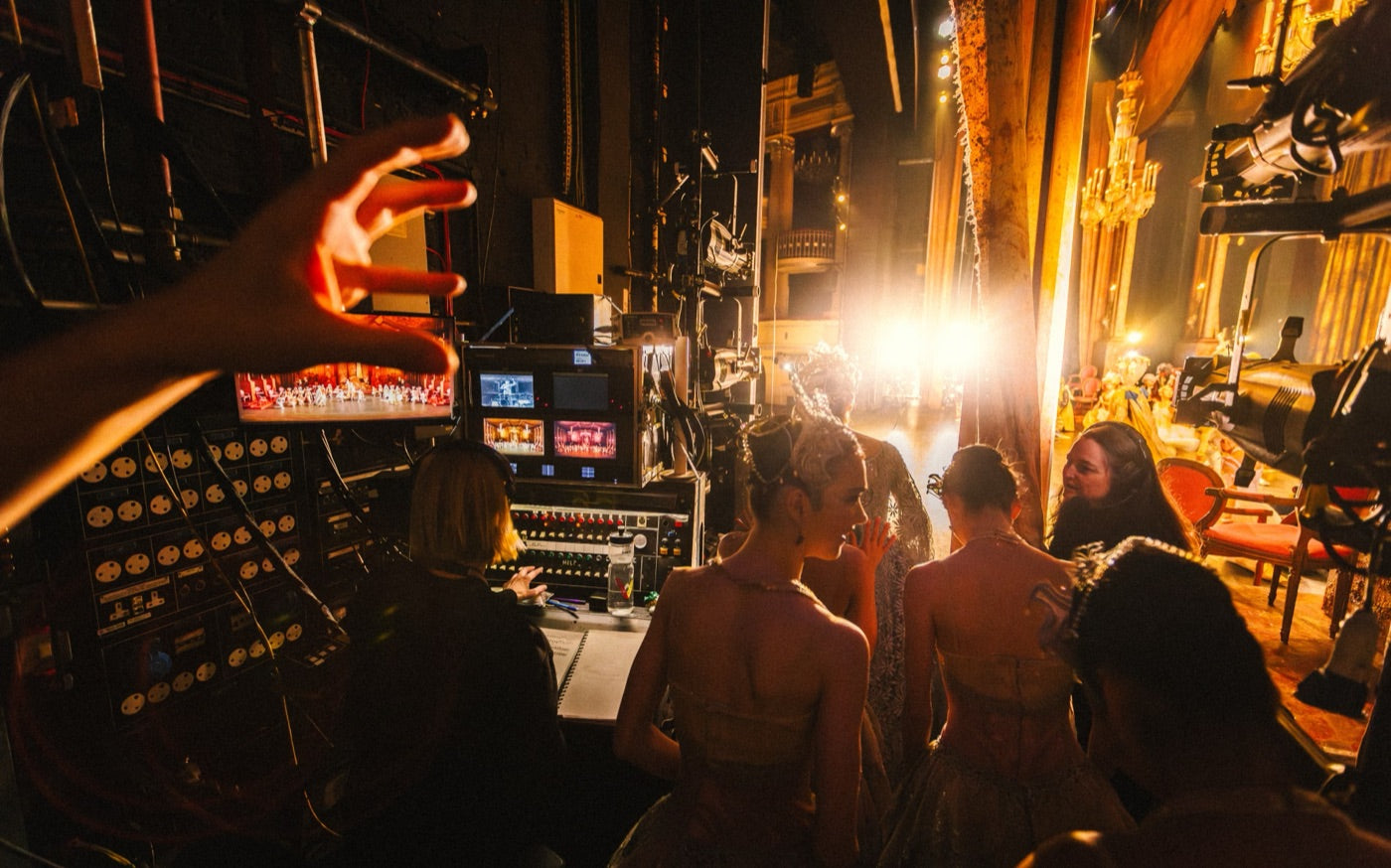 Backstage at a ballet performance, dancers waiting in the wings by the control desk