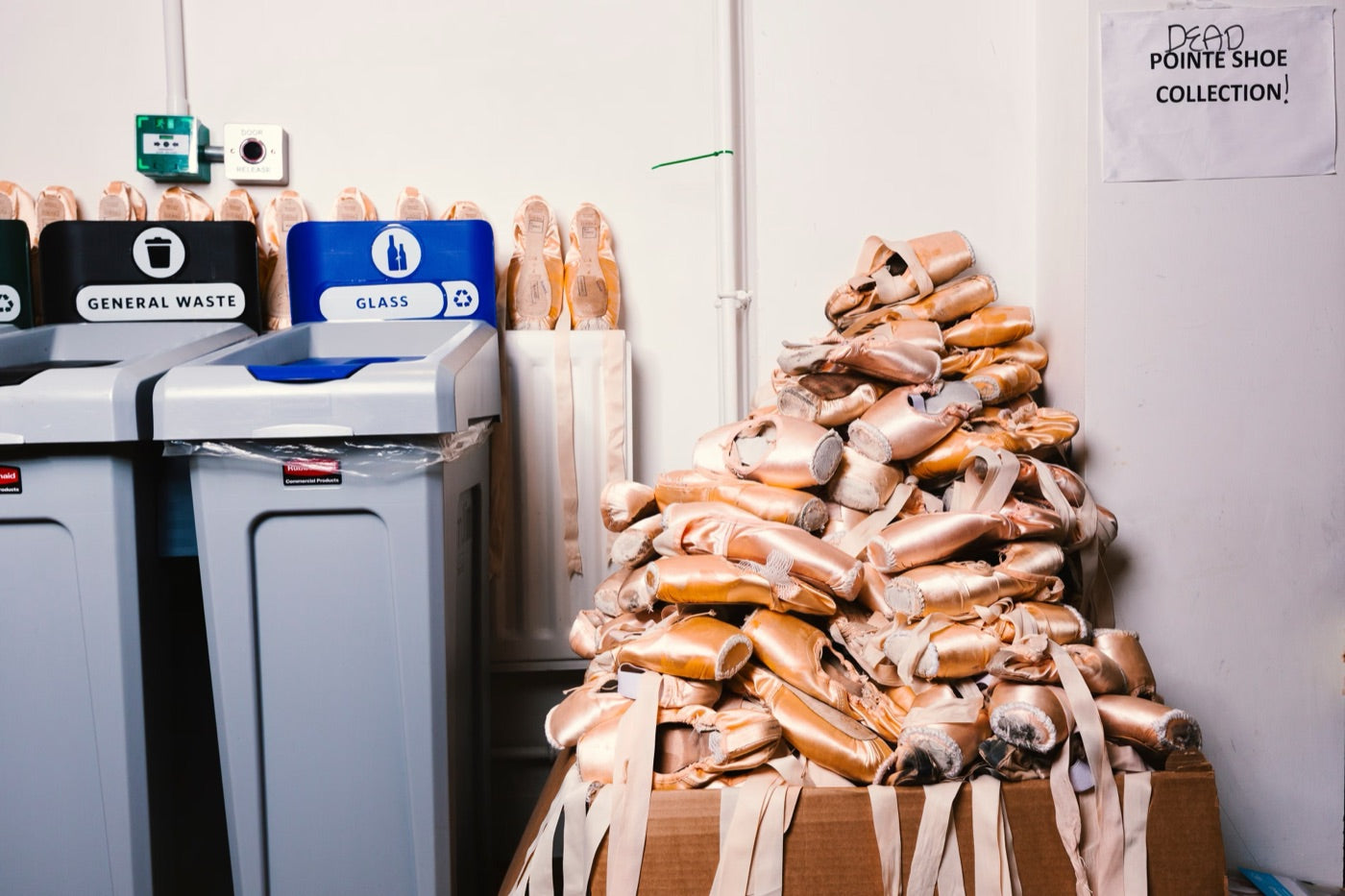 A pile of worn pointe shoes next to the recycling bins